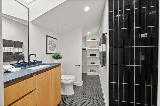 bathroom with tile patterned flooring, vanity, toilet, and vaulted ceiling with skylight