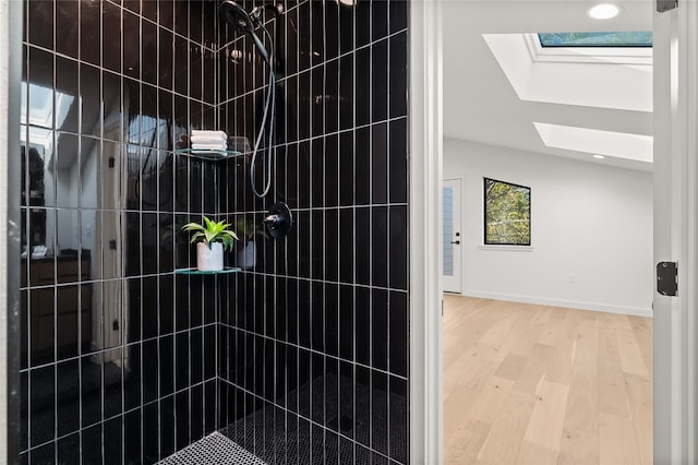 room details with a tile shower, a skylight, and hardwood / wood-style flooring