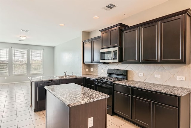 kitchen featuring backsplash, a kitchen island, black appliances, light tile patterned flooring, and kitchen peninsula