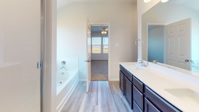 bathroom with a tub, ceiling fan, lofted ceiling, vanity, and hardwood / wood-style flooring