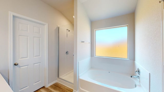 bathroom with plus walk in shower, hardwood / wood-style floors, and vaulted ceiling