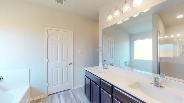 bathroom with hardwood / wood-style floors, vanity, and a tub