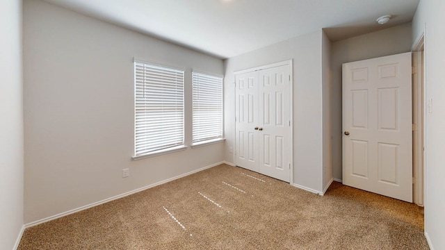 unfurnished bedroom with a closet and light colored carpet