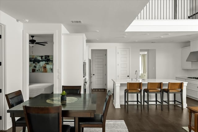 dining room featuring ceiling fan, sink, and dark wood-type flooring