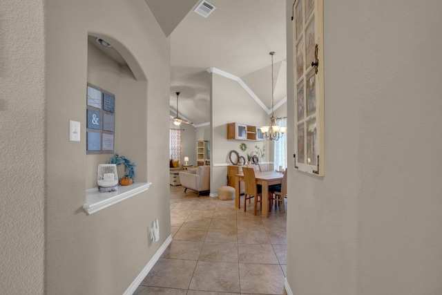 hallway featuring a notable chandelier, light tile patterned floors, and vaulted ceiling