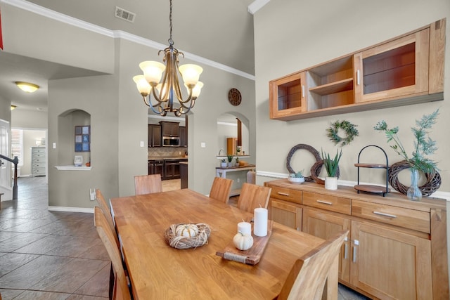 tiled dining space featuring a towering ceiling, crown molding, and a chandelier