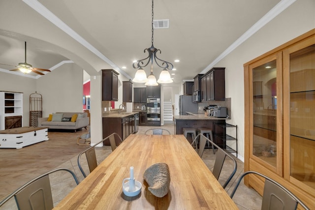 dining room featuring vaulted ceiling, crown molding, sink, and ceiling fan with notable chandelier