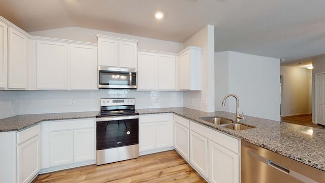 kitchen with sink, light stone countertops, light wood-type flooring, appliances with stainless steel finishes, and white cabinetry