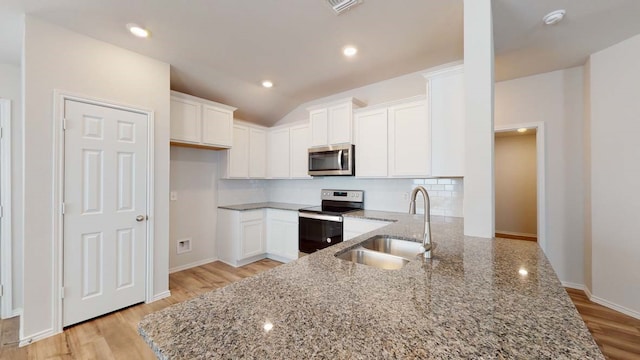 kitchen with light stone countertops, appliances with stainless steel finishes, light wood-type flooring, sink, and white cabinetry