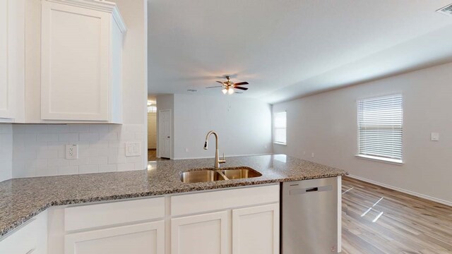 kitchen with stone counters, white cabinetry, sink, stainless steel dishwasher, and light hardwood / wood-style floors