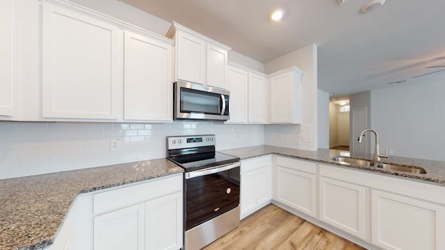 kitchen featuring appliances with stainless steel finishes, light wood-type flooring, sink, stone countertops, and white cabinets