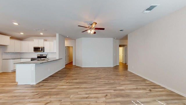 kitchen with white cabinets, ceiling fan, light stone countertops, light hardwood / wood-style floors, and stainless steel appliances