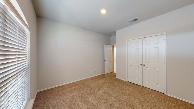 unfurnished bedroom with light colored carpet and a closet