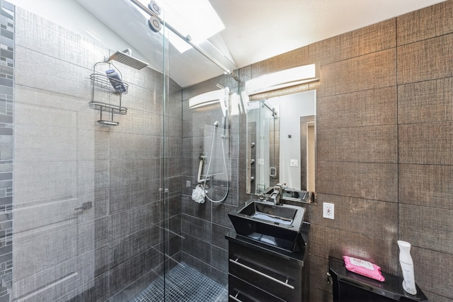 bathroom with vanity, a shower with door, and tile walls