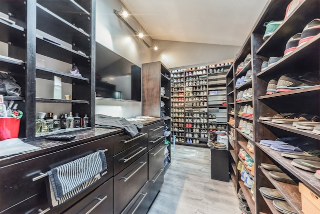 walk in closet with vaulted ceiling and light wood-type flooring