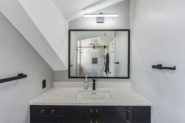 bathroom featuring vanity, a shower with shower door, and lofted ceiling