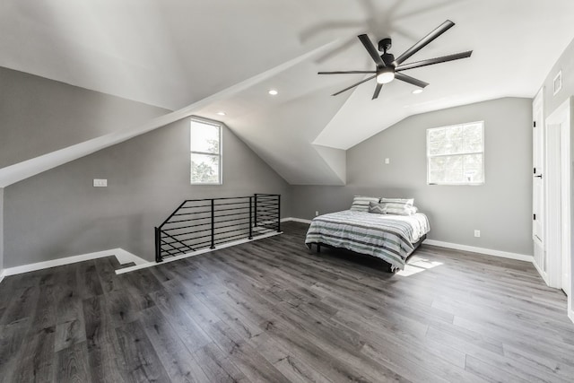 unfurnished bedroom featuring multiple windows, vaulted ceiling, ceiling fan, and dark wood-type flooring