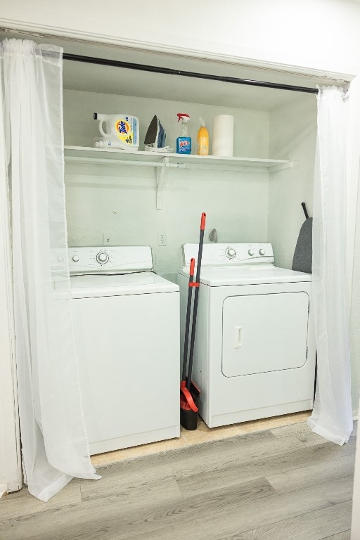 clothes washing area featuring light hardwood / wood-style flooring and washer and clothes dryer