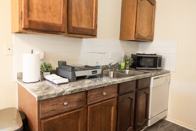 kitchen featuring tasteful backsplash, dark hardwood / wood-style flooring, dishwasher, and sink