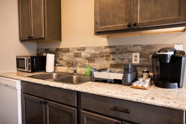 kitchen featuring dishwasher, sink, decorative backsplash, light stone countertops, and dark brown cabinets