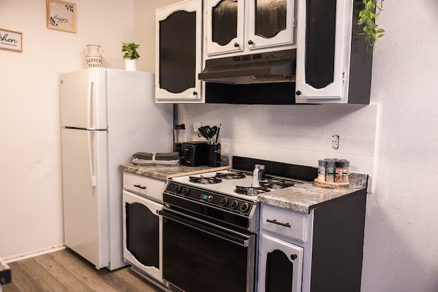 kitchen with gas range, white cabinetry, tasteful backsplash, light stone counters, and light wood-type flooring