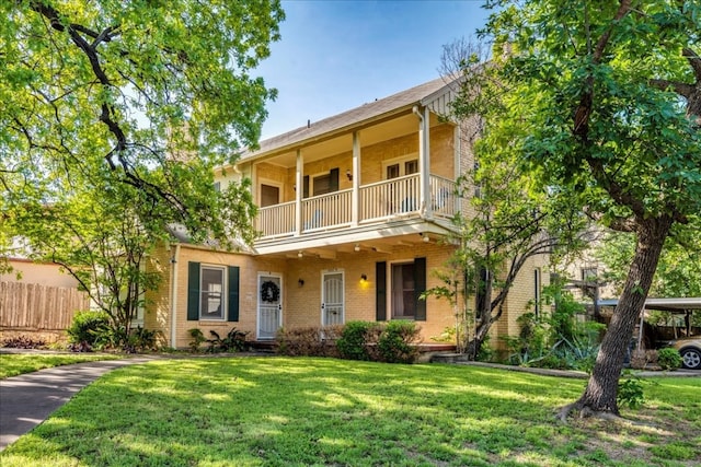 view of front facade featuring a balcony and a front yard