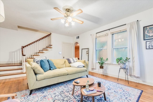 living room featuring wood-type flooring, a textured ceiling, and ceiling fan