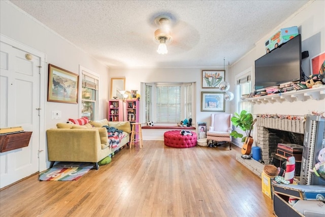 living room featuring wood-type flooring, a textured ceiling, a brick fireplace, and ceiling fan