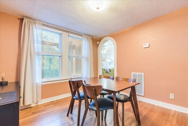 dining space with a textured ceiling and light hardwood / wood-style flooring