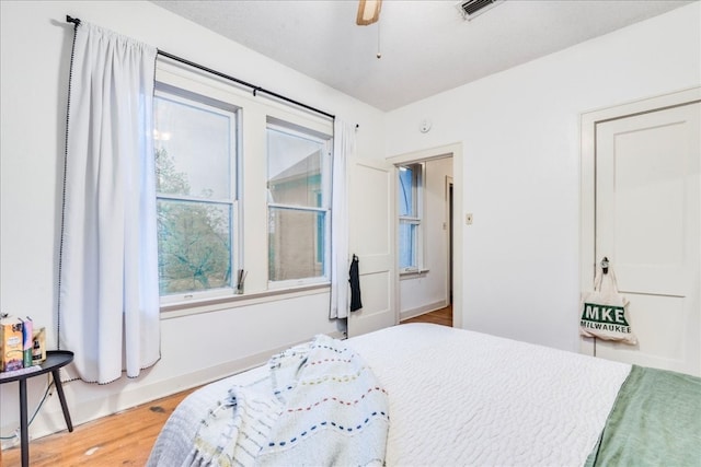 bedroom with multiple windows, wood-type flooring, and ceiling fan