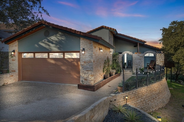 view of front of house featuring stucco siding, aphalt driveway, stone siding, an attached garage, and a tiled roof