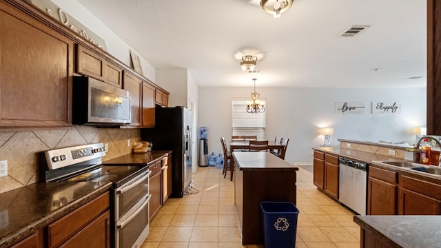 kitchen featuring appliances with stainless steel finishes, backsplash, sink, light tile patterned floors, and a kitchen island