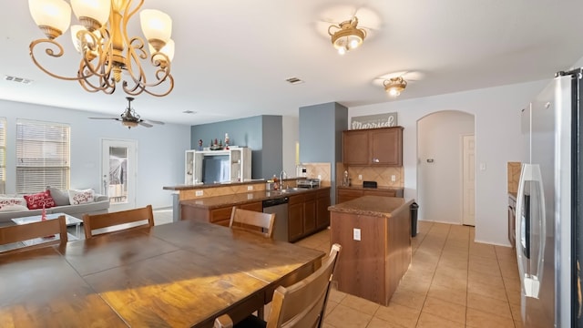 tiled dining room featuring ceiling fan with notable chandelier and sink