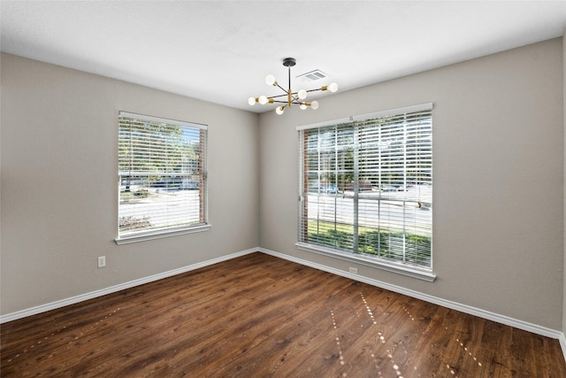 unfurnished room with a notable chandelier, dark hardwood / wood-style floors, and a healthy amount of sunlight