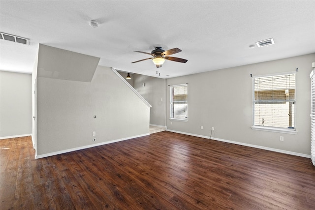 interior space with a textured ceiling, ceiling fan, and dark wood-type flooring