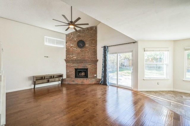 unfurnished living room featuring ceiling fan, hardwood / wood-style flooring, vaulted ceiling, and a brick fireplace