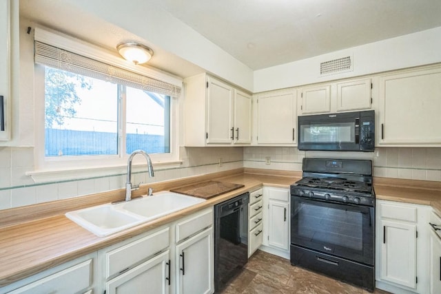 kitchen with black appliances, decorative backsplash, white cabinetry, and sink