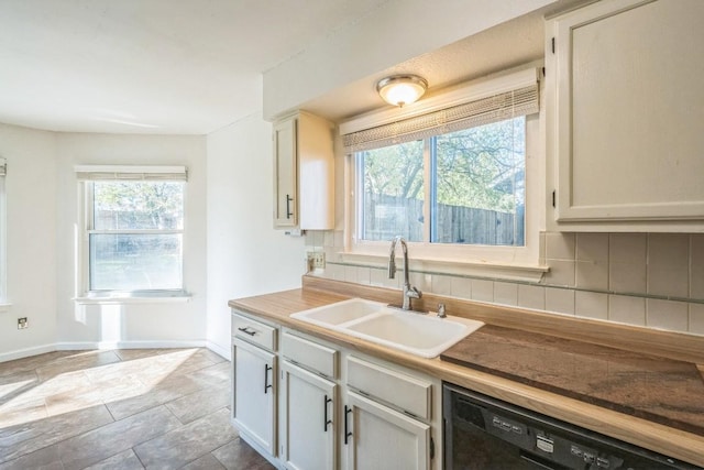 kitchen with decorative backsplash, sink, white cabinets, and black dishwasher