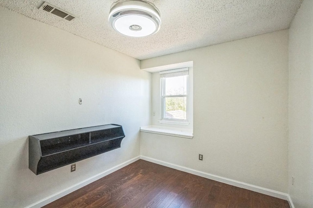 empty room featuring dark wood-type flooring and a textured ceiling