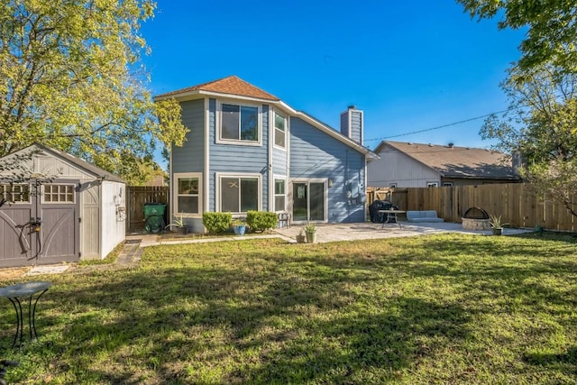 back of property with a lawn, a patio, a shed, and an outdoor fire pit