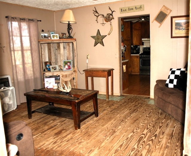 living room featuring hardwood / wood-style flooring, ceiling fan, crown molding, and a textured ceiling