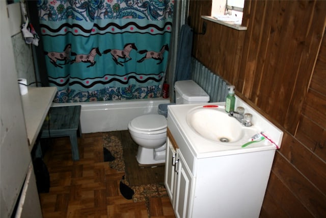 full bathroom featuring parquet flooring, vanity, wooden walls, shower / bath combo with shower curtain, and toilet