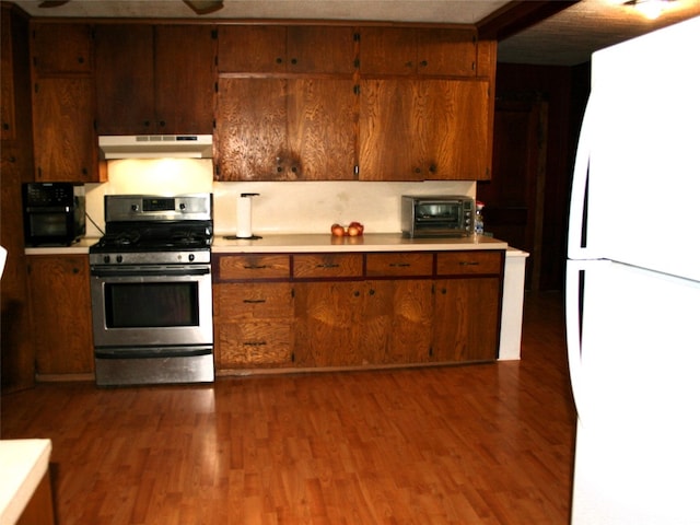 kitchen with dark hardwood / wood-style flooring, white refrigerator, and stainless steel gas range