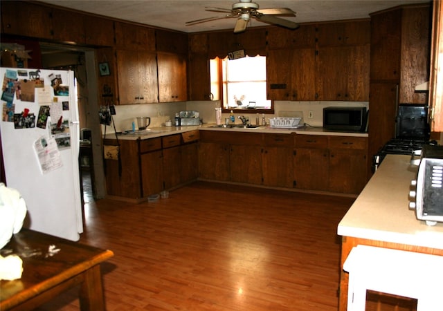 kitchen featuring ceiling fan, white refrigerator, dark hardwood / wood-style flooring, and sink