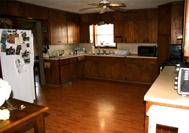 kitchen with freestanding refrigerator, light countertops, ceiling fan, a sink, and built in microwave