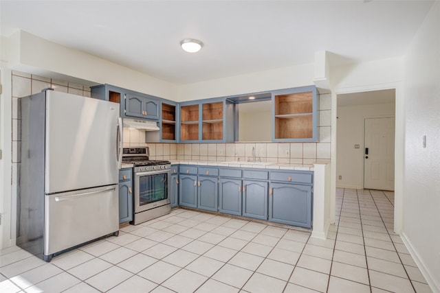 kitchen with sink, stainless steel appliances, tasteful backsplash, blue cabinets, and light tile patterned floors