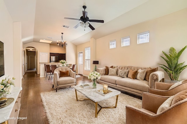 living room with ceiling fan with notable chandelier, vaulted ceiling, and dark wood-type flooring