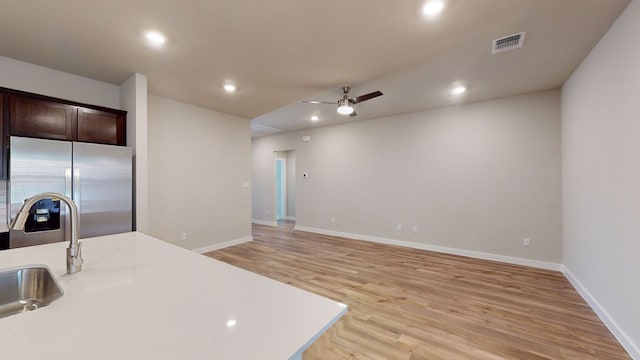 kitchen featuring ceiling fan, dark brown cabinets, stainless steel refrigerator, and light hardwood / wood-style flooring