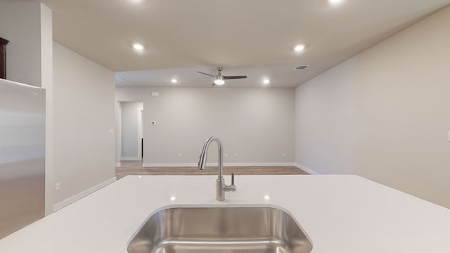 room details featuring stainless steel fridge, light wood-type flooring, ceiling fan, and sink