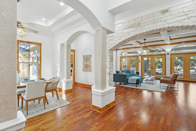 interior space featuring beam ceiling, ornate columns, french doors, wood-type flooring, and ornamental molding